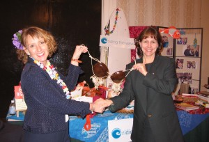 Veronica Adams shaking hands and presenting cocoanut brazzier to smiling woman at business women's conference.