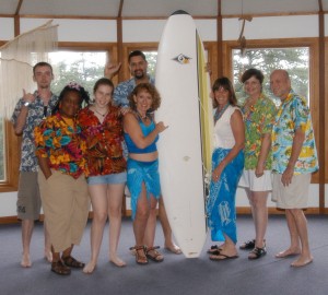 Riding the wave team members with surfboard in beach ware.
