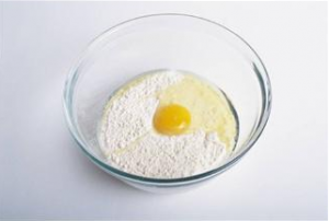 Bowl with flour and broken egg in preparation for cooking